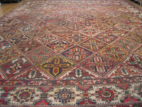 Large multicolored rug displays a repeating geometric diamond pattern over a wooden floor.