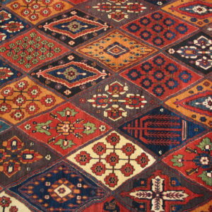 A multi-colored rug featuring a patchwork of detailed diamond motifs in red, navy, orange, and cream.