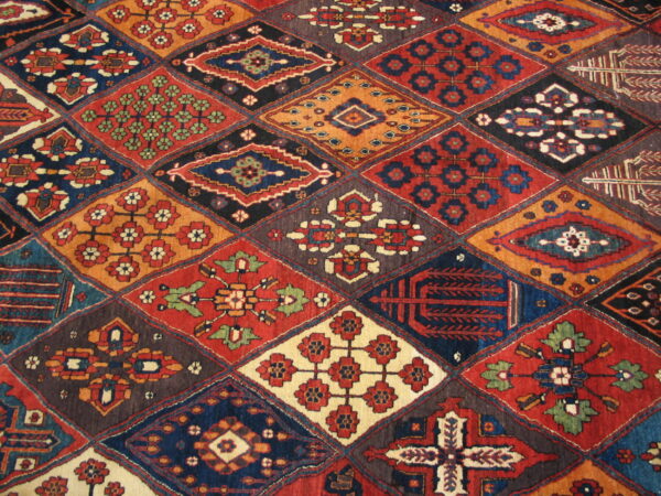 A multi-colored rug featuring a patchwork of detailed diamond motifs in red, navy, orange, and cream.