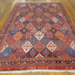 Large multi-colored rug featuring complex geometric diamond motifs resting on light brown hardwood flooring.