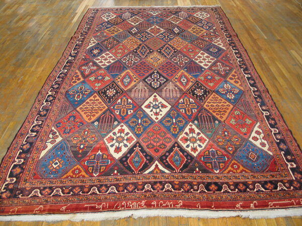 Large multi-colored rug featuring complex geometric diamond motifs resting on light brown hardwood flooring.