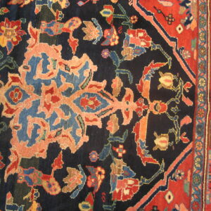 Ornate floral rug detail showing a dark navy field next to a wide red patterned border.