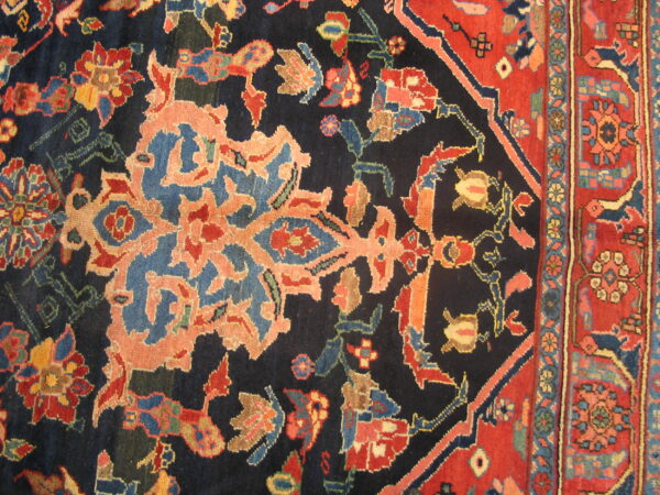Ornate floral rug detail showing a dark navy field next to a wide red patterned border.
