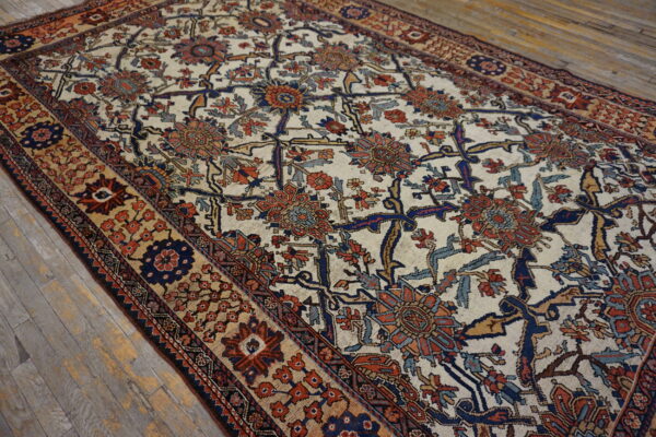 A traditional rug with an ivory field, featuring navy, rust, and blue floral motifs, laid on distressed wood floorboards.
