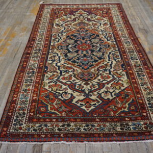 Red, navy, and cream traditional pattern rug with low pile lies on distressed wood planks.