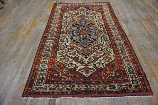 Red, navy, and cream traditional pattern rug with low pile lies on distressed wood planks.