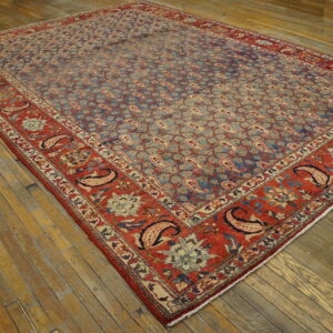 Low pile rug featuring a faded blue paisley field and contrasting wide red border on worn wood planks.
