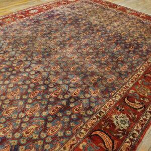 Traditional blue and red rug featuring an intricate field of paisley motifs on pale wood planks.