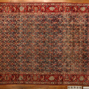 Low-pile rug with a repeating teal and red paisley pattern and wide decorative red borders on wood floors.