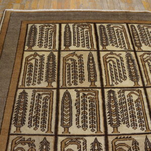 Geometric tan and brown rug with stylized tree motifs and a striped border on wood flooring.