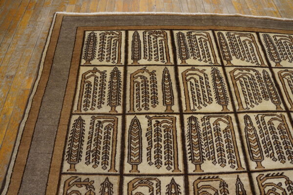 Geometric tan and brown rug with stylized tree motifs and a striped border on wood flooring.