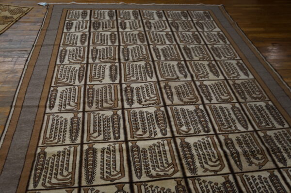 Geometric brown and cream rug with a tiled pattern featuring stylized vertical abstract designs on hardwood.