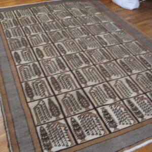 Brown and beige rug featuring an all-over grid design of symmetrical tree motifs upon light wood flooring.