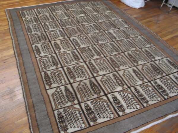 Brown and beige rug featuring an all-over grid design of symmetrical tree motifs upon light wood flooring.