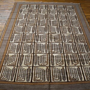 Brown and cream rug with abstract vertical motifs in a grid pattern on hardwood flooring.