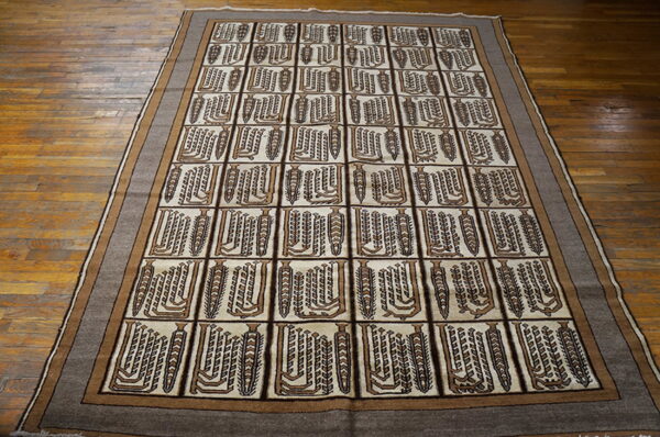 Brown and cream rug with abstract vertical motifs in a grid pattern on hardwood flooring.