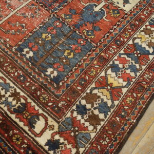 A compartmentalized rug featuring pictorial trees in red, blue, and brown squares rests on worn wood flooring.