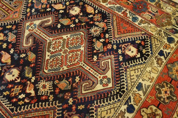 Dark blue field rug featuring intricate red, beige, and blue tribal motifs, including stylized animals.