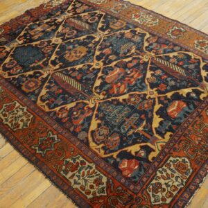 Low-pile rug with a navy, rust, and gold geometric lattice pattern on light plank flooring.