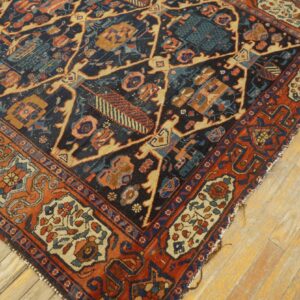 A low pile rug featuring navy, rust, and beige geometric patterns rests on light, worn wooden floorboards.