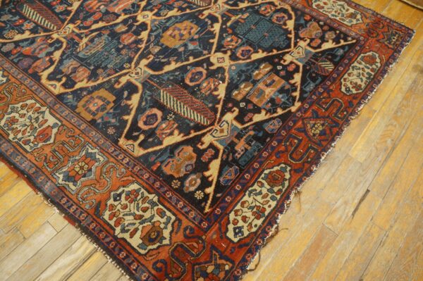 A low pile rug featuring navy, rust, and beige geometric patterns rests on light, worn wooden floorboards.