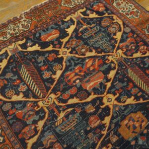 Detailed view of a low-pile rug with navy, rust, gold, and teal traditional geometric patterns on wood flooring.
