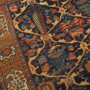 Ornate rug detail featuring a navy blue field, rust border, and stylized floral motifs on wood planks.