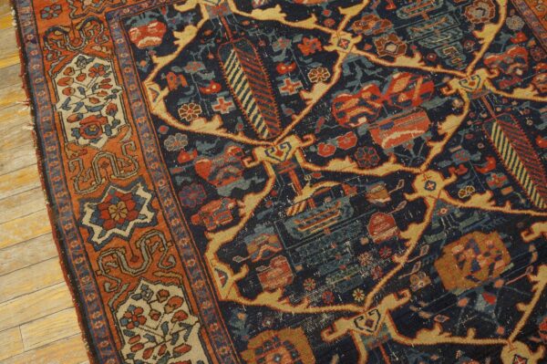 Ornate rug detail featuring a navy blue field, rust border, and stylized floral motifs on wood planks.