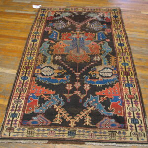 Long dark rug with contrasting red, blue, and yellow stylized geometric and figural patterns on wood floor.