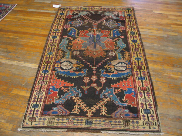 Long dark rug with contrasting red, blue, and yellow stylized geometric and figural patterns on wood floor.