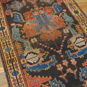 Geometric runner rug featuring a dark brown field bordered by yellow, blue, and rust colors on wood floor.