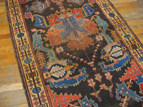 Geometric runner rug featuring a dark brown field bordered by yellow, blue, and rust colors on wood floor.