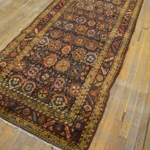 Dark runner rug with repeating blue, red, and green floral medallions on distressed yellow wood planks.
