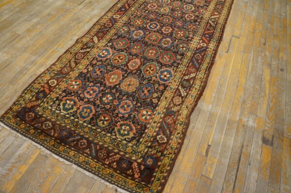 Dark runner rug with repeating blue, red, and green floral medallions on distressed yellow wood planks.