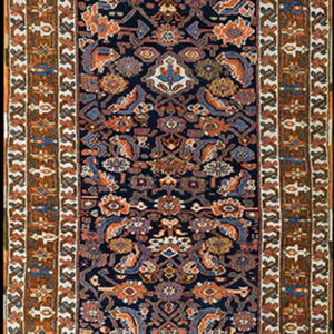 Narrow runner rug with a dark field, dense rust and blue floral motifs, and geometric brown and cream borders.