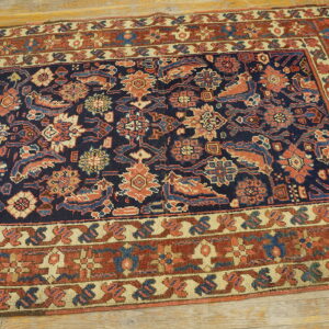 Low-pile rug featuring a densely patterned navy field and rust-toned borders on light hardwood.