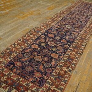 Navy runner with dense floral patterns in rust and blue, displayed on worn, distressed wood planks.