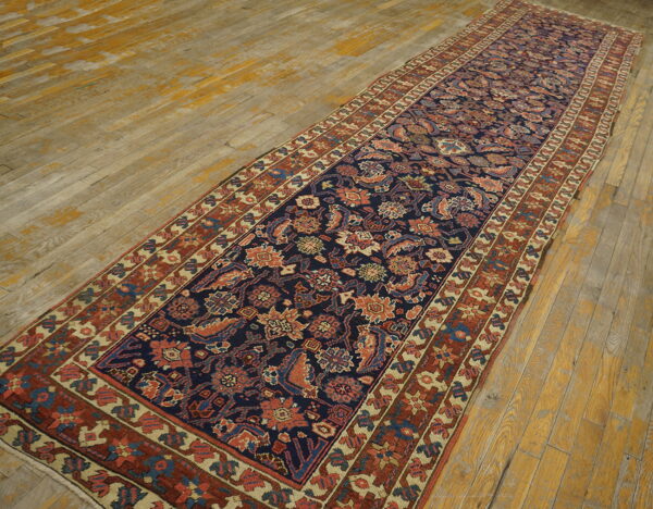 Navy runner with dense floral patterns in rust and blue, displayed on worn, distressed wood planks.