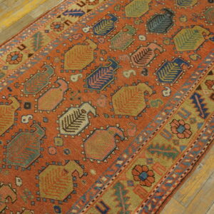 Orange and multicolor geometric runner rug featuring stylized vase motifs rests on light wood floors.