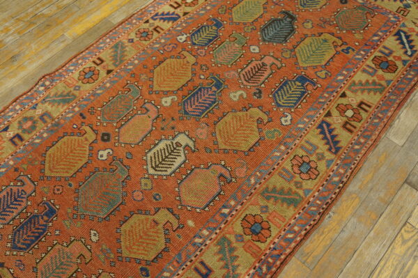 Orange and multicolor geometric runner rug featuring stylized vase motifs rests on light wood floors.