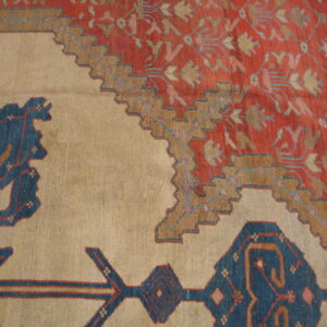 Stepped brown borders separate a busy rust-red floral pattern from a plain beige rug field.