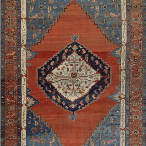 Ornate rust and blue geometric rug featuring a large stepped medallion and decorative borders with script.