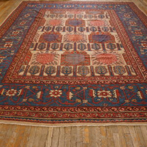 Geometric blue, red, and cream rug featuring repeating medallions rests on rustic wood flooring.