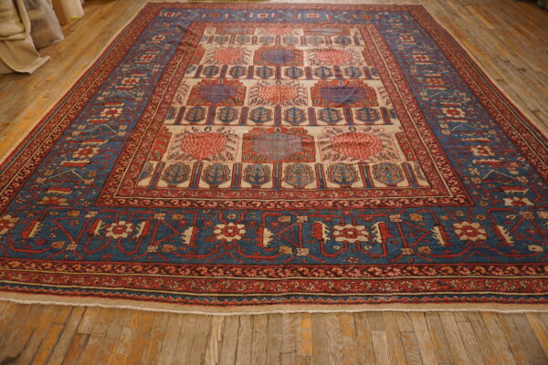 Geometric blue, red, and cream rug featuring repeating medallions rests on rustic wood flooring.