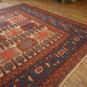 Geometric red, blue, and cream patterned rug laid out on a rustic, wide plank wood floor.