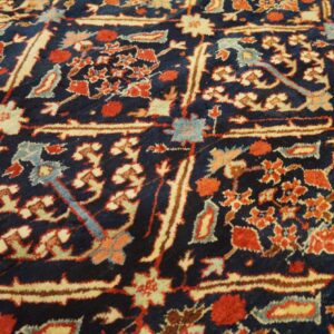 Intricate red, cream, and blue floral motifs densely cover the dark blue rug pile.