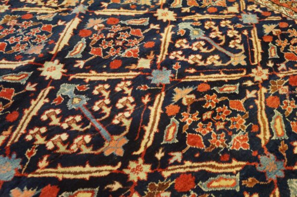 Intricate red, cream, and blue floral motifs densely cover the dark blue rug pile.