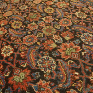 Traditional low-pile rug with dense red, blue, and green floral motifs on a dark field.