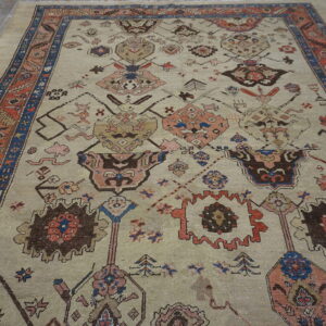 Low-pile rug in light beige with tribal medallions and a rust and blue border on wood planks.
