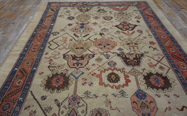 Low-pile rug in light beige with tribal medallions and a rust and blue border on wood planks.